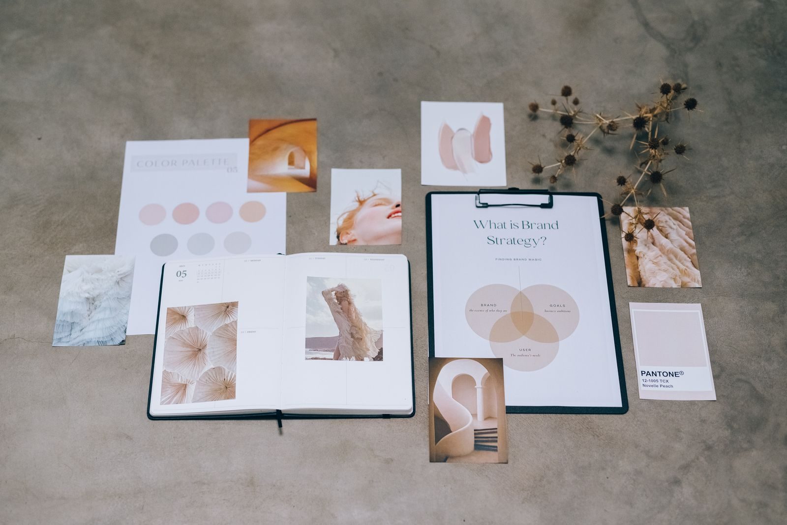Flat lay de elementos de marca com paletas de cores e documentos de planejamento sobre concreto