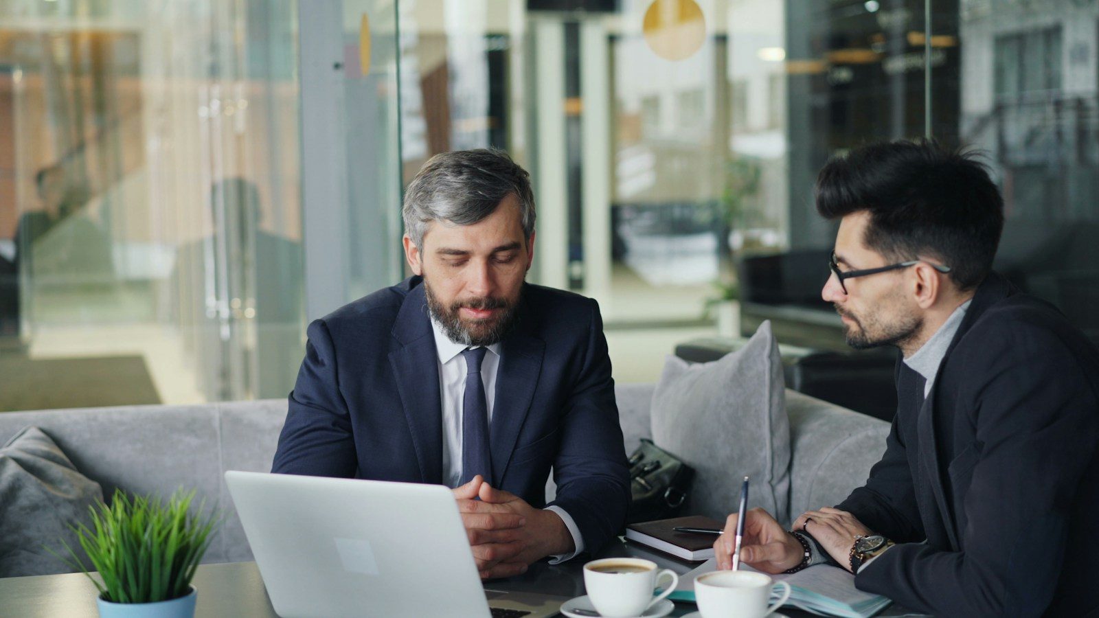 Dois homens sentados à mesa trabalhando em um notebook