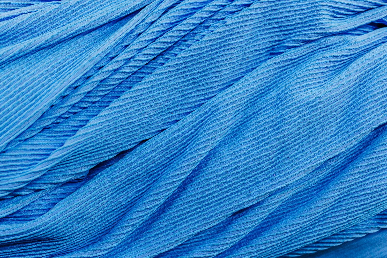 Close de tecido plissado azul com textura, dobras e padrões detalhados