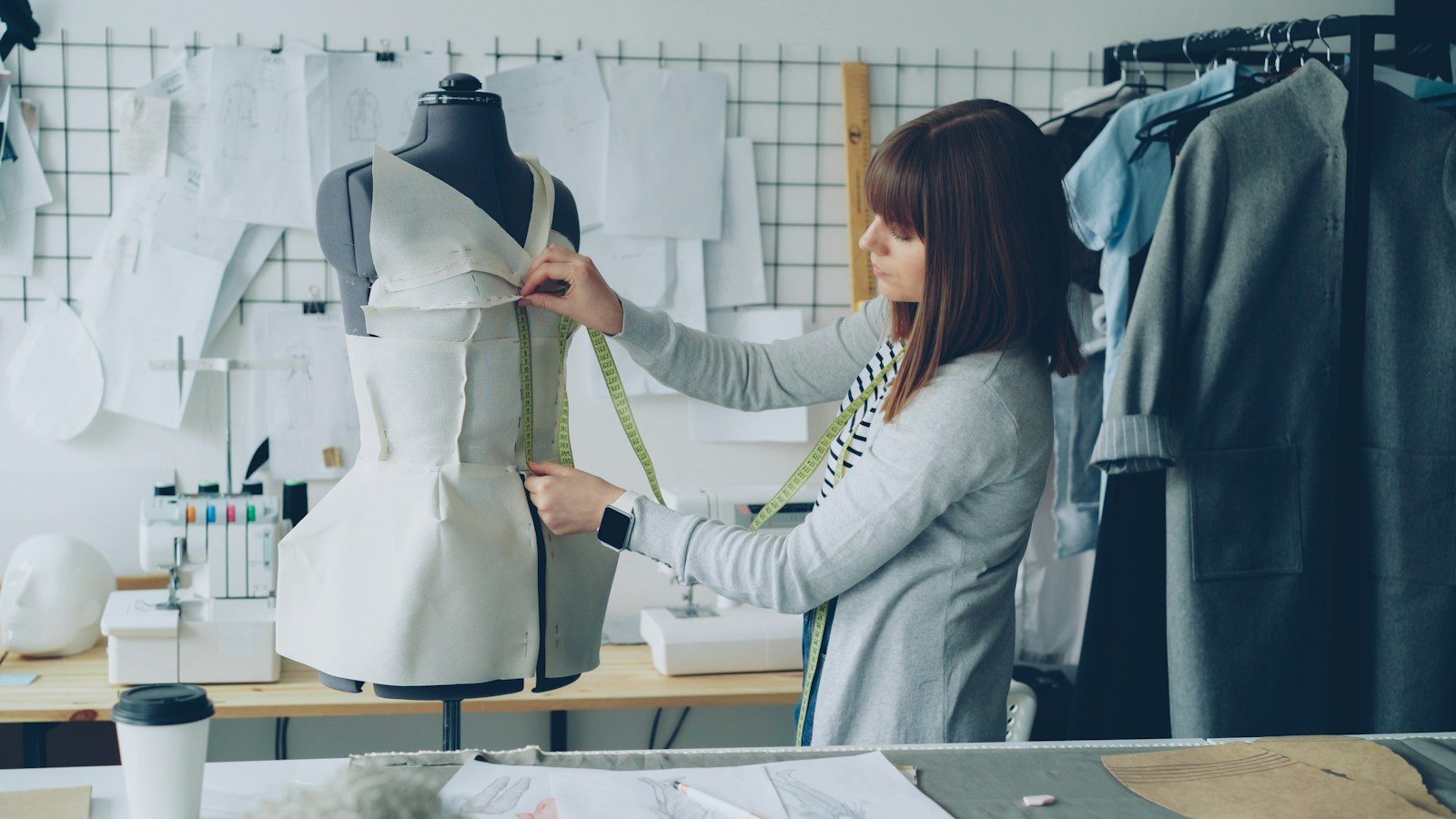 Estilista mede uma peça de roupa em um manequim