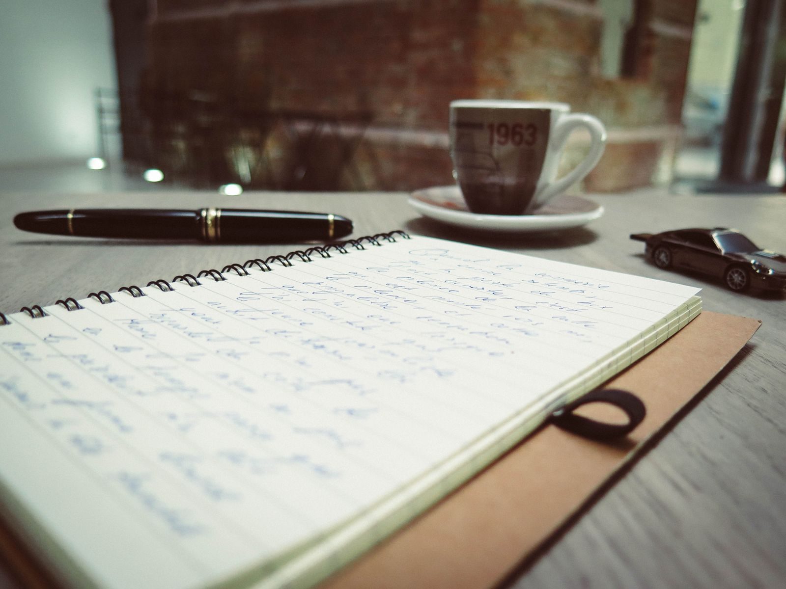 Espaço de trabalho acolhedor com café, anotações à mão e uma caneta sobre a mesa