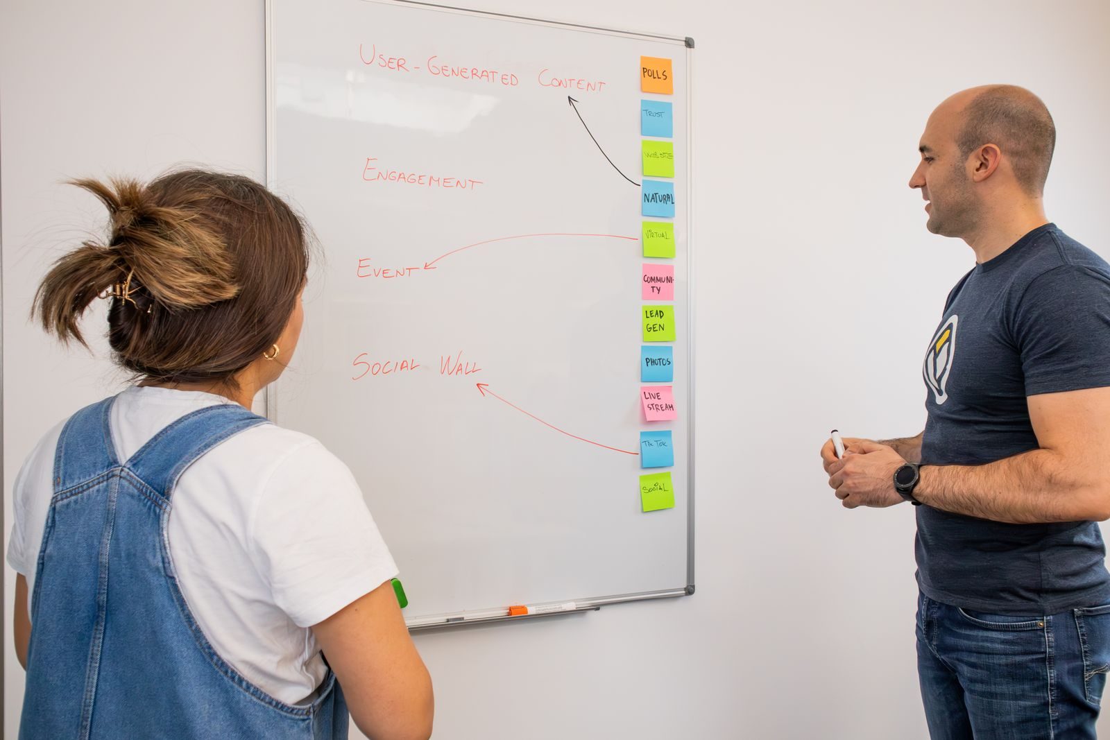 Dois colegas colaboram em estratégia de marketing no quadro branco em escritório moderno
