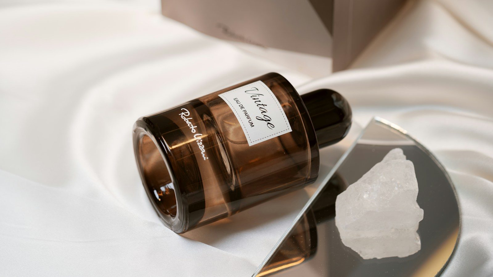 Frasco de perfume de vidro marrom sobre cetim branco