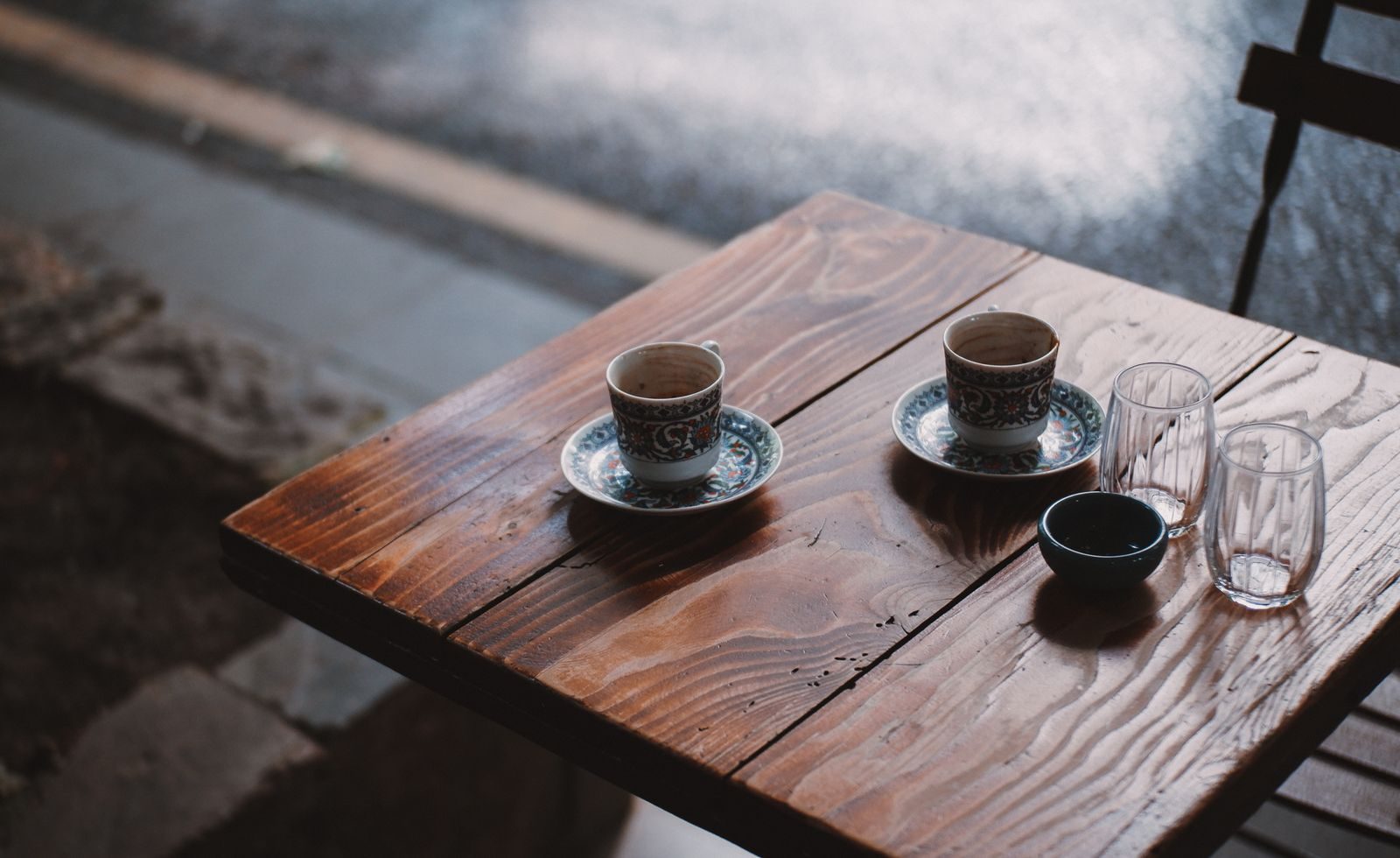 Mesa de madeira de café com xícaras e copos vazios, criando um ambiente aconchegante