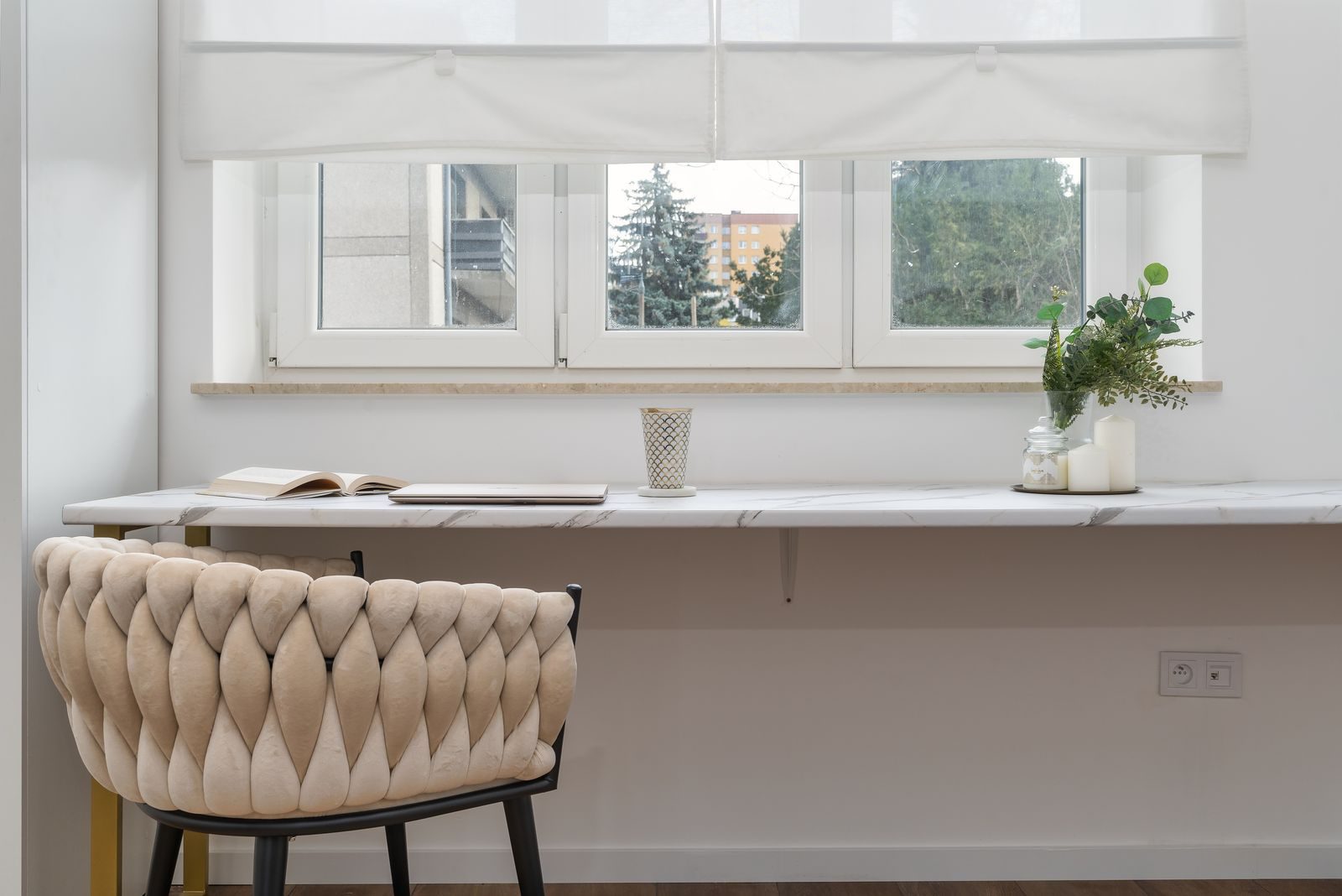 Ambiente interno elegante com poltrona confortável, mesa branca moderna e plantas