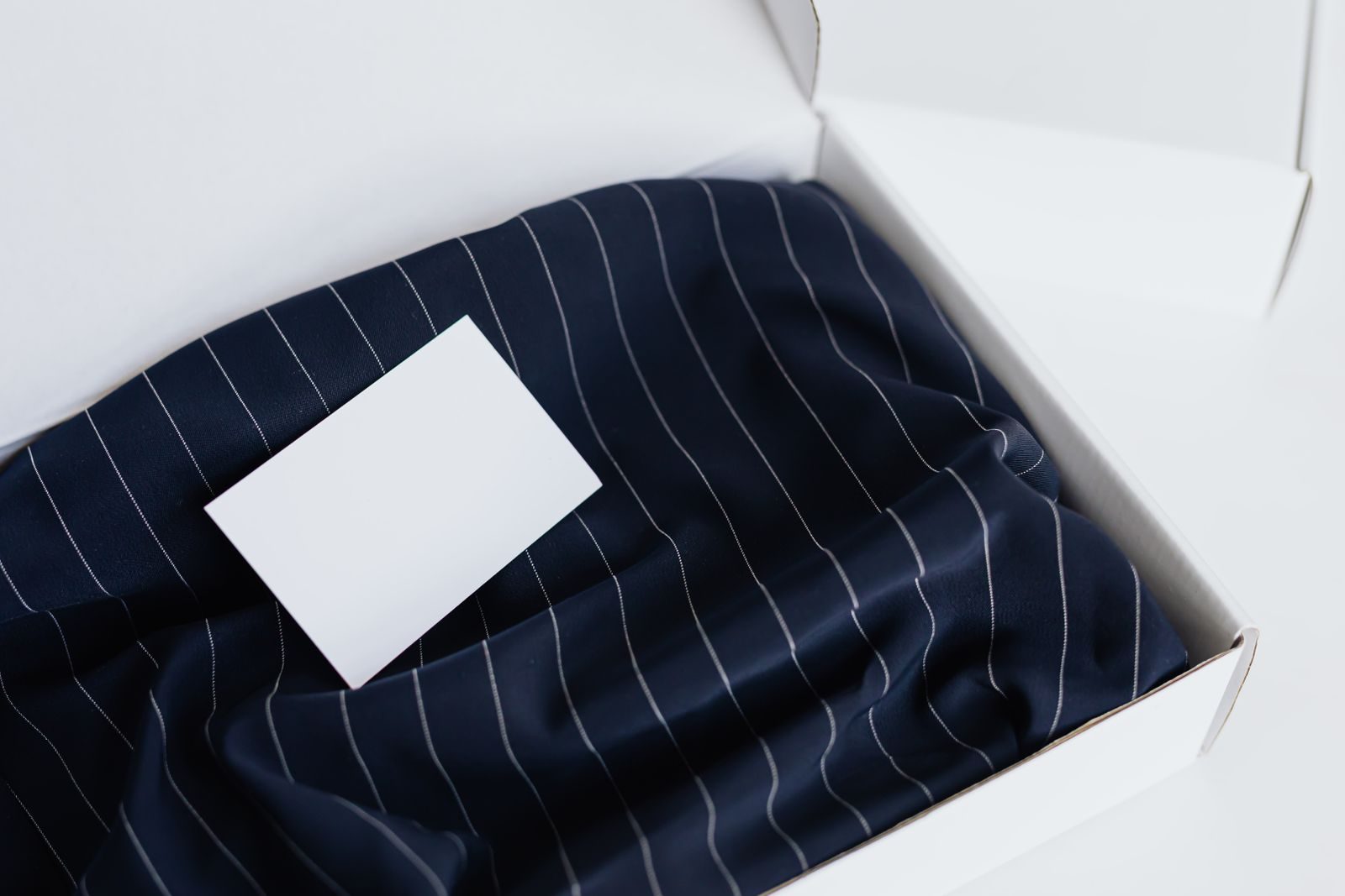 Cartão de visita elegante sobre tecido de seda em uma caixa sofisticada, ideal para mockups