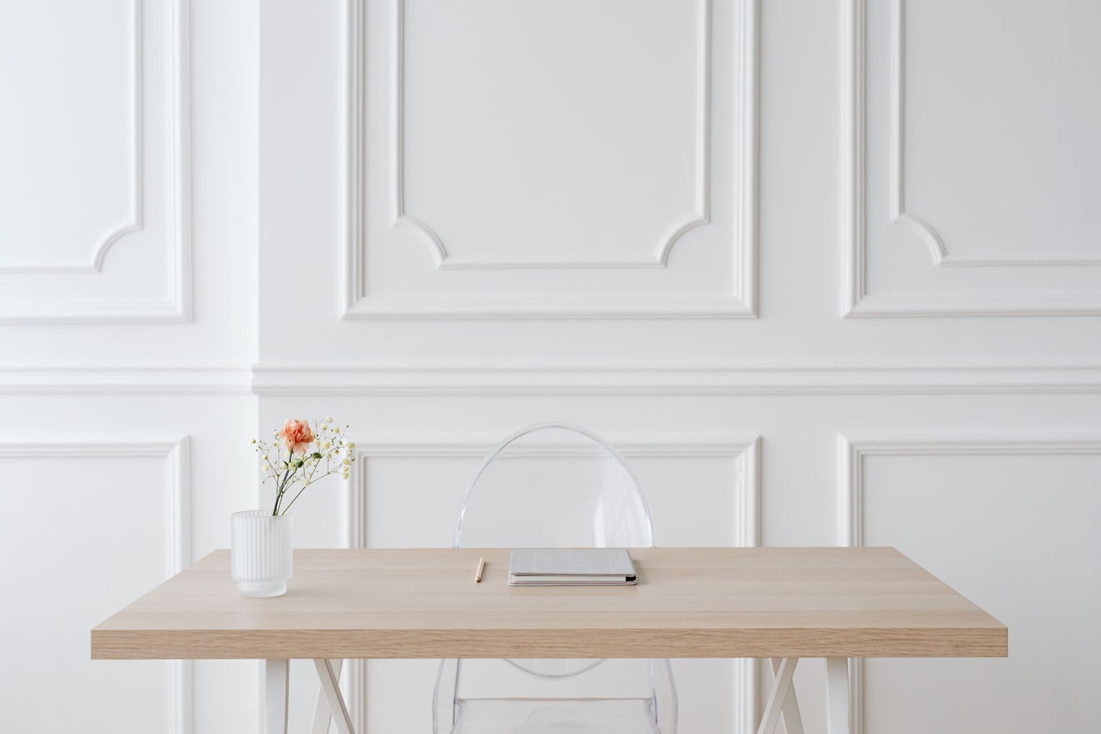 Espaço de trabalho minimalista e elegante com mesa de madeira, vaso de vidro e parede de painéis