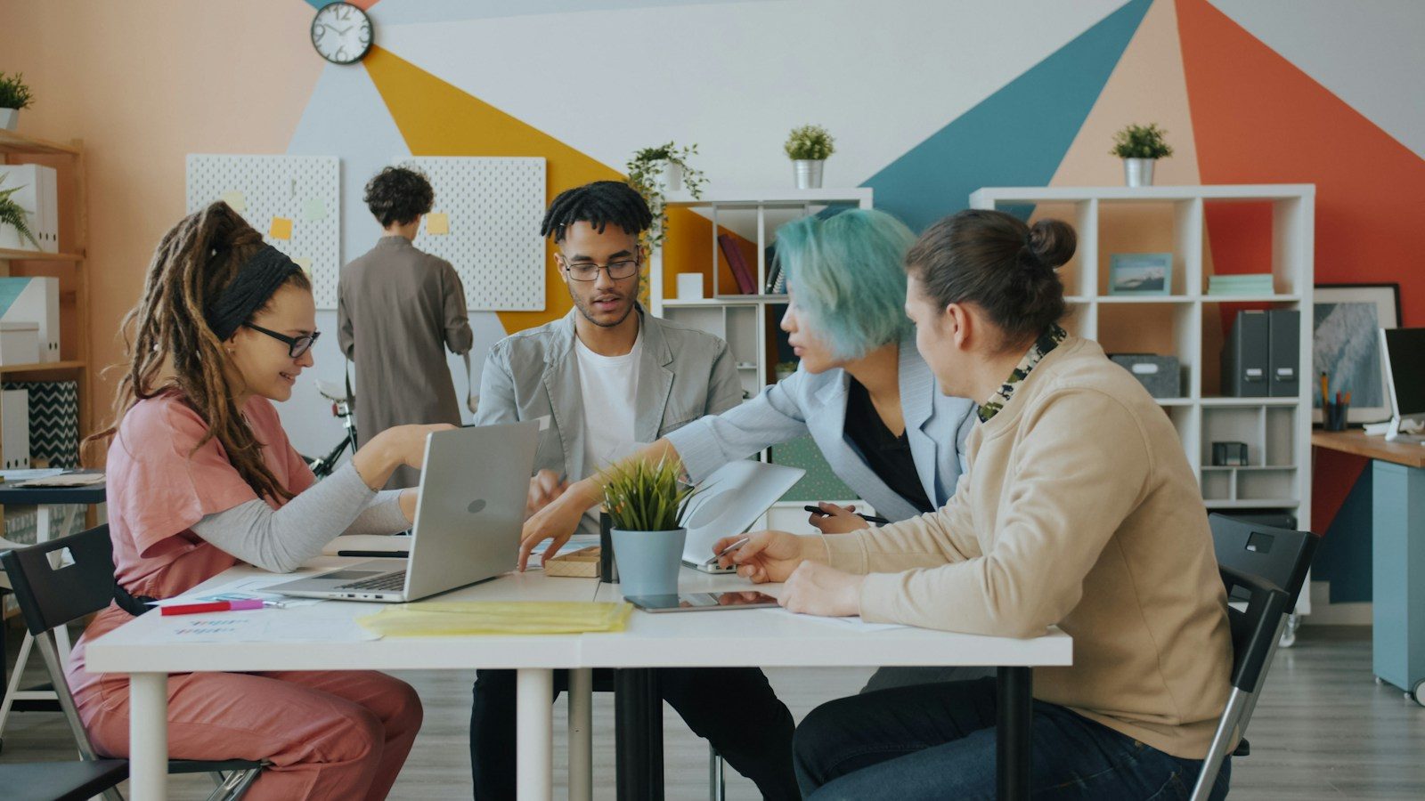Grupo diverso de pessoas colaborando ao redor de uma mesa em escritório moderno