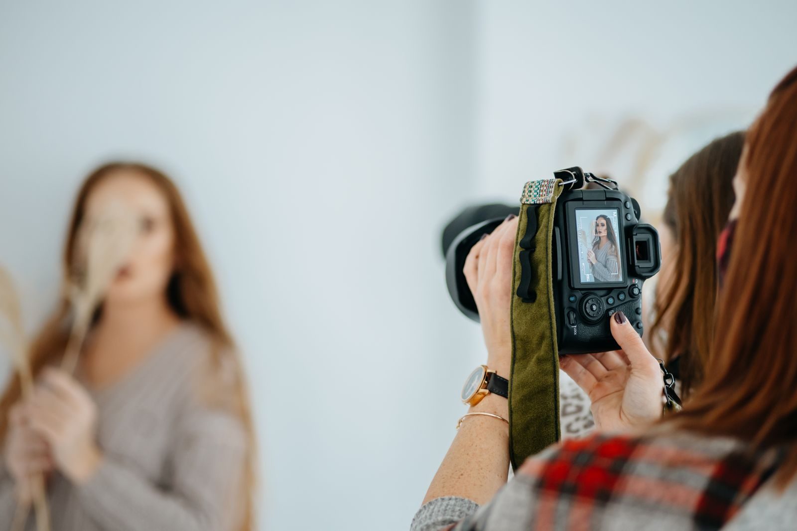 Fotógrafo fotografando uma modelo em estúdio com câmera DSLR, em retrato criativo
