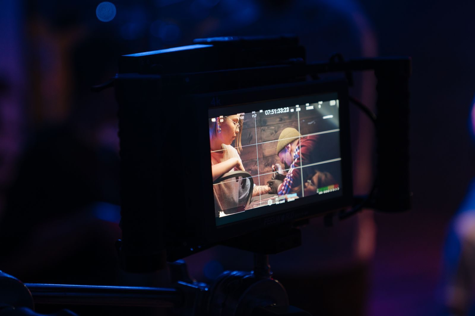 Equipe de filmagem ajustando a câmera no set iluminado por luzes neon
