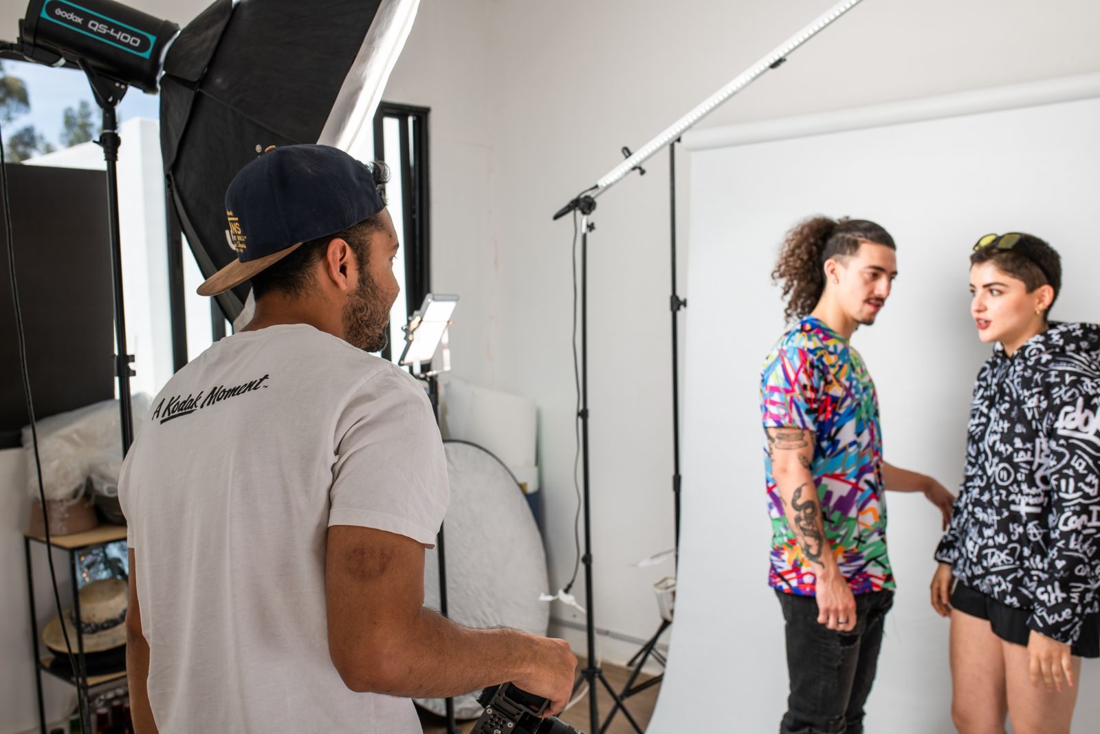 Sessão de fotos vibrante em estúdio com fotógrafo e modelos em ação, unindo criatividade e colaboração