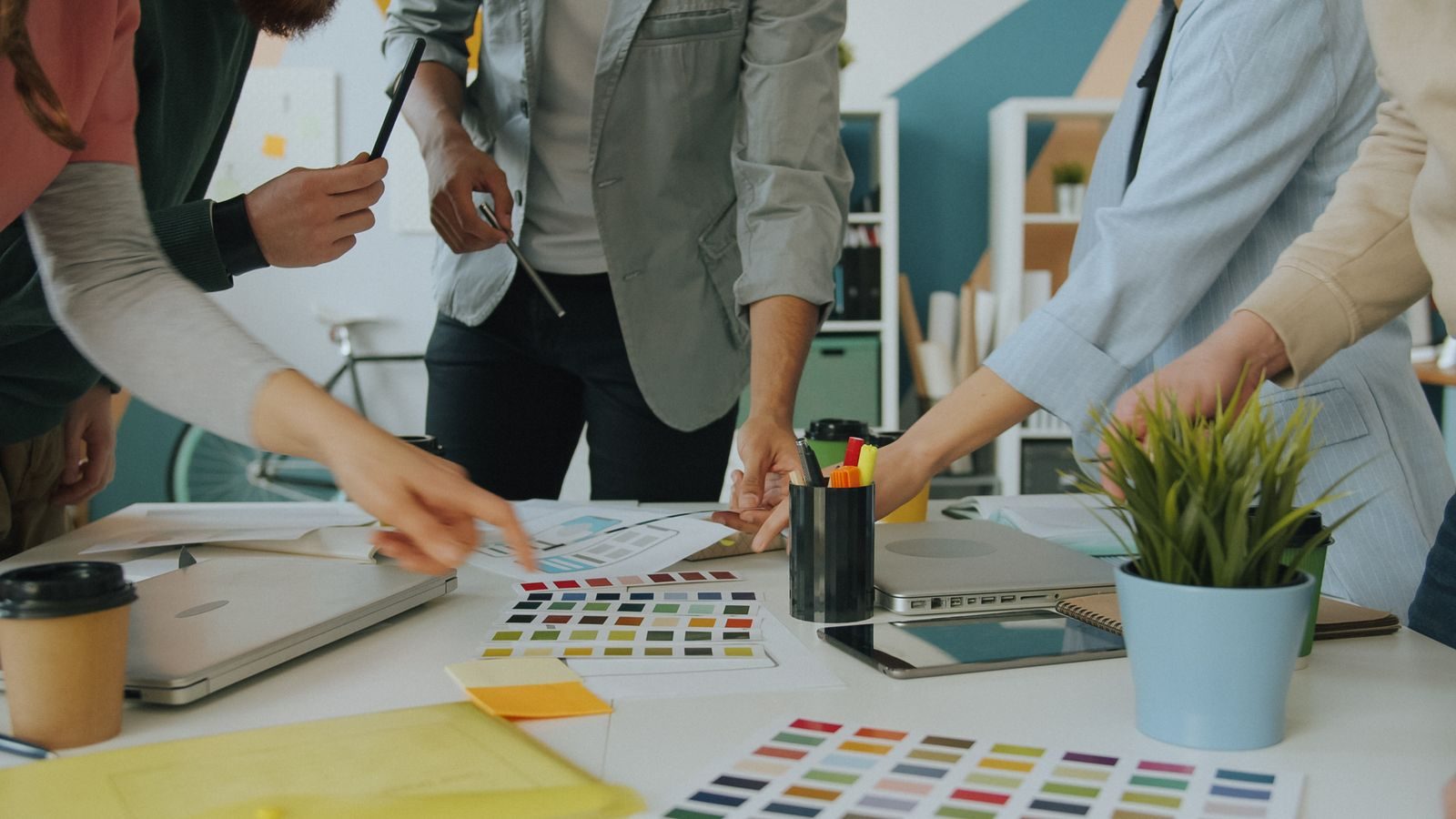 Equipe colaborando com amostras de cores e elementos de design em um escritório moderno