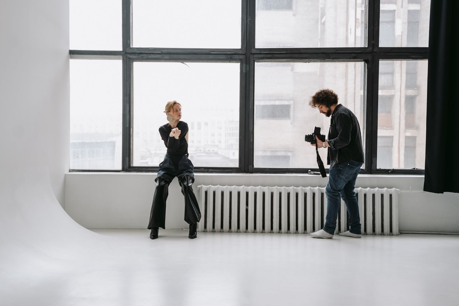 Fotógrafo clicando modelo posando em estúdio claro e minimalista