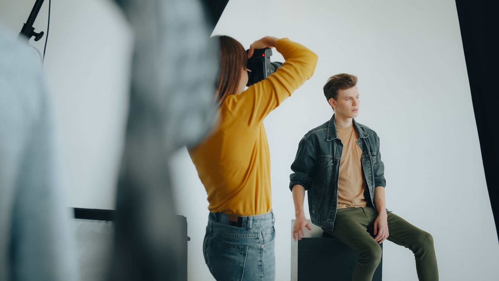 Fotógrafo clicando modelo masculino em ensaio num estúdio moderno