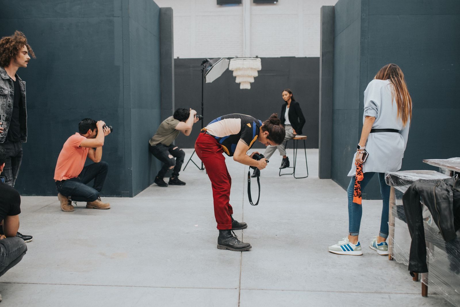 Grupo de fotógrafos clicando modelo em estúdio interno moderno