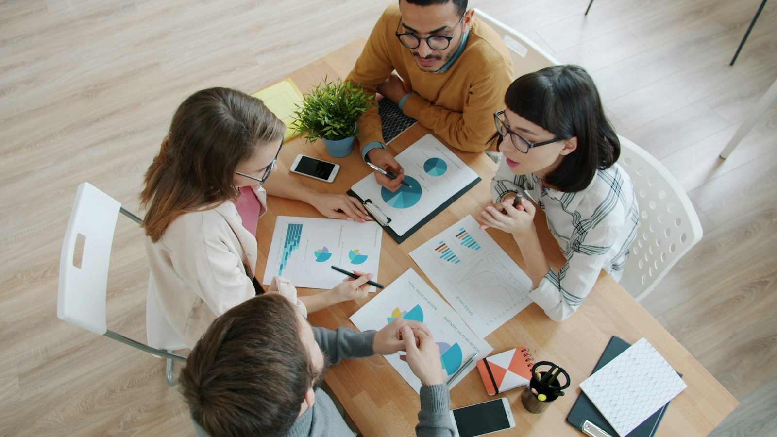 Quatro pessoas colaborando ao redor de uma mesa com documentos