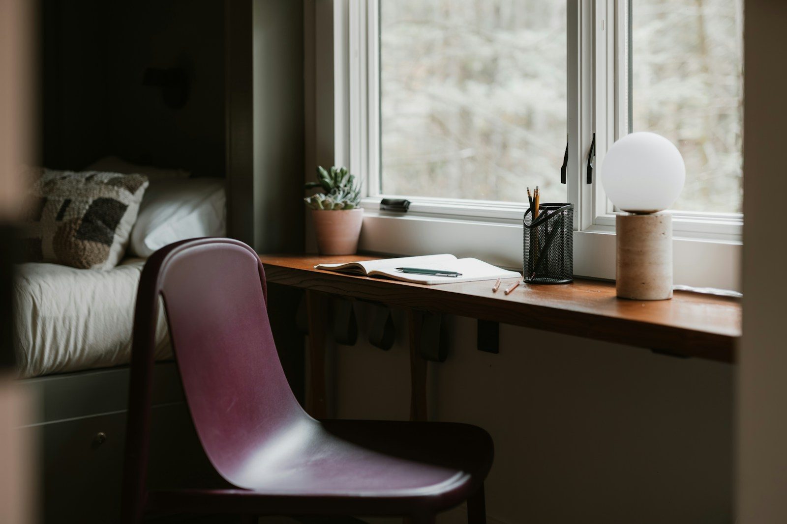 Cadeira e mesa perto de uma janela com luminária
