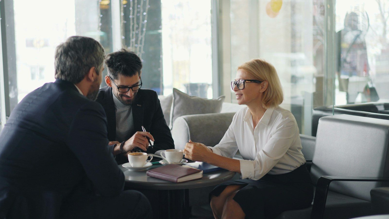 Dois homens e uma mulher sentados à mesa conversando