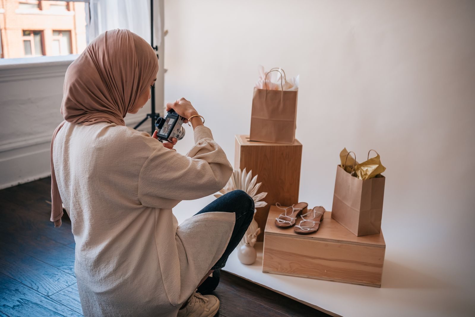Mulher muçulmana de hijab fotografando produtos em um estúdio bem iluminado