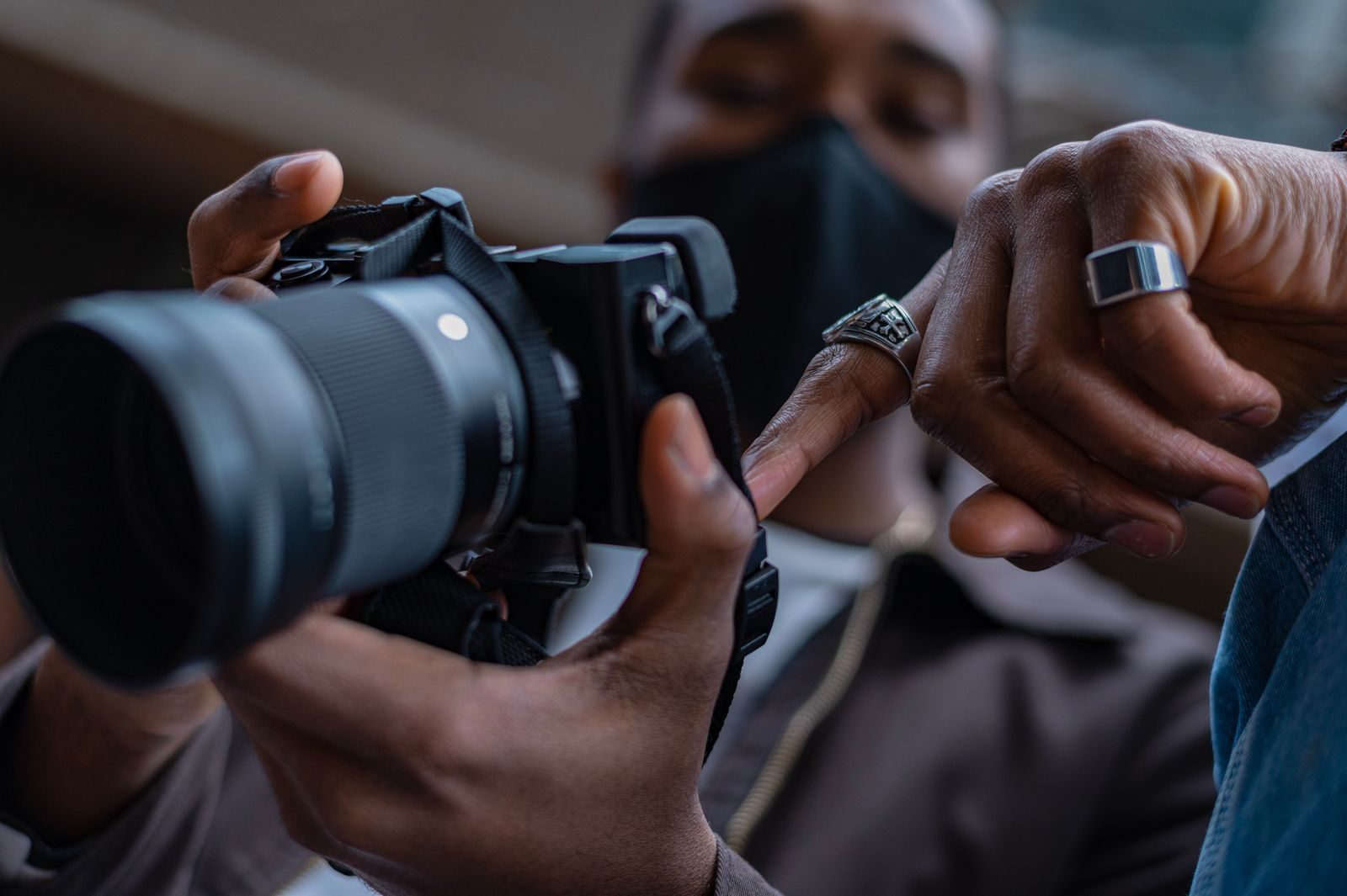 Close de mãos segurando e ajustando uma câmera DSLR em ambiente interno