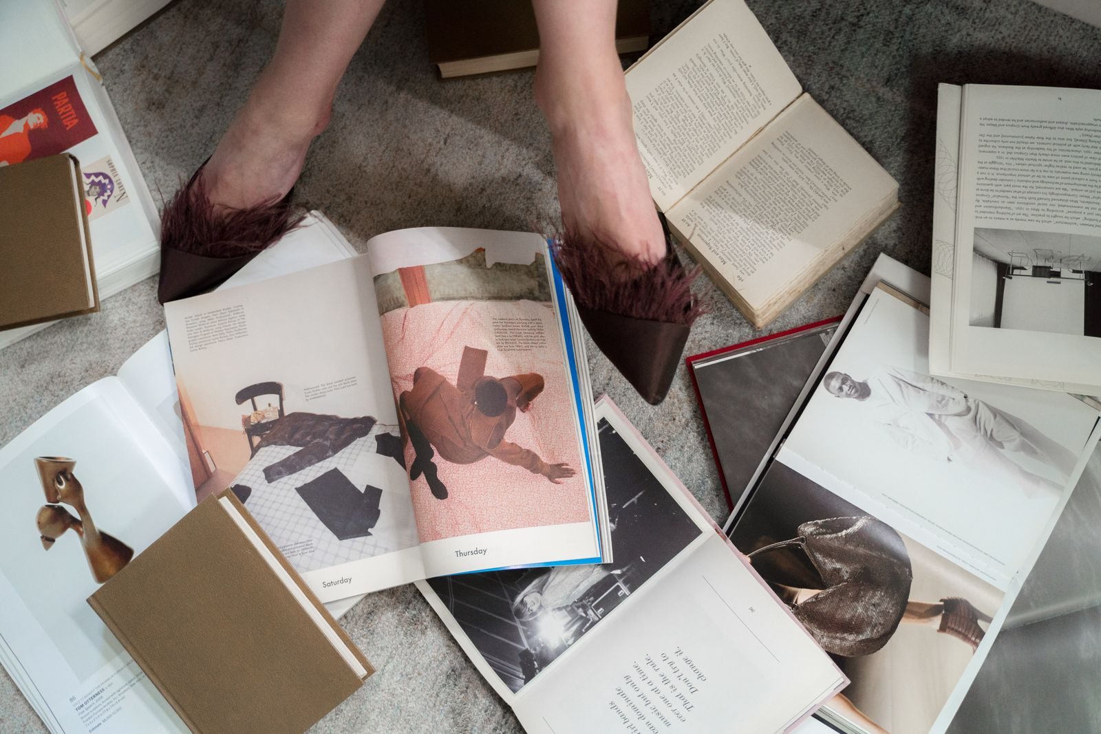 Livros abertos dispostos sobre um carpete, com sapatos estilosos à vista