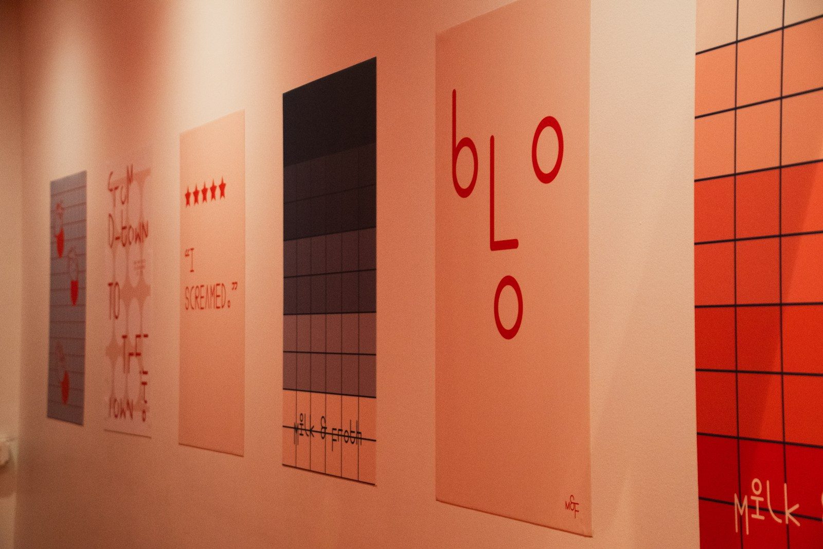 Série de pôsteres gráficos com texto e padrões geométricos na parede