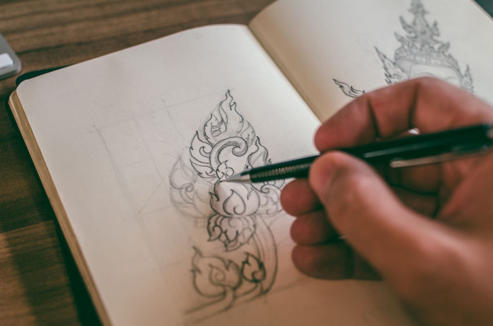 Close de mão desenhando um projeto detalhado em sketchbook com lapiseira