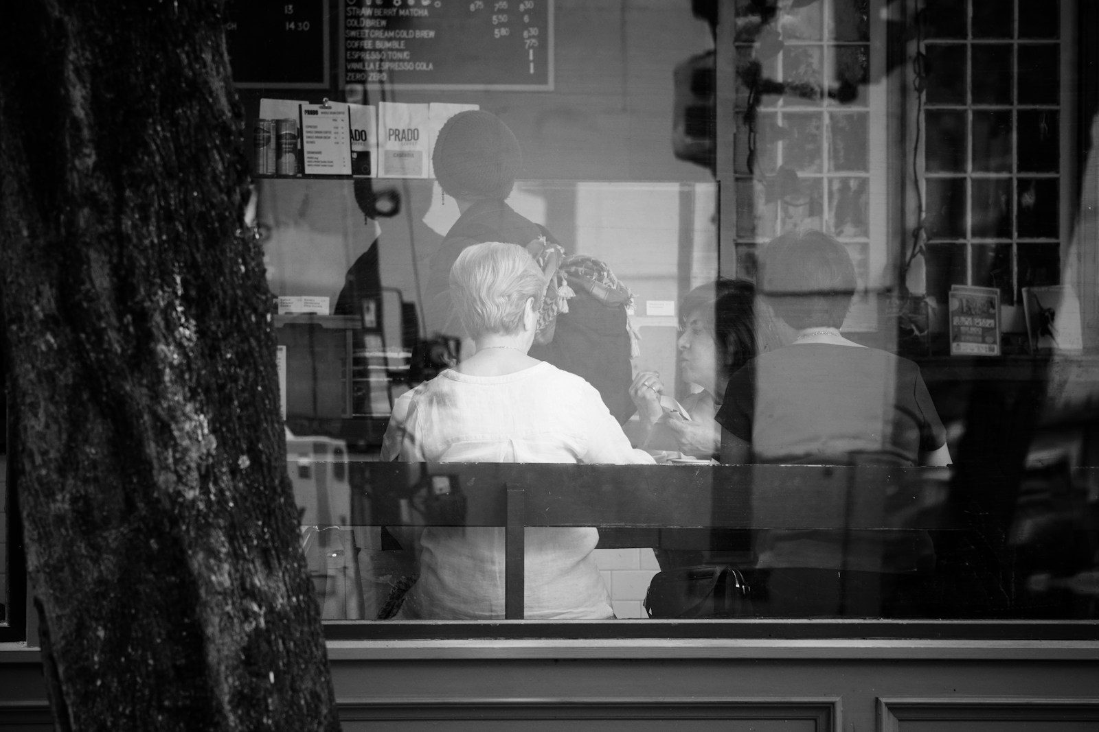 Pessoa em um café vista através de uma janela com reflexos