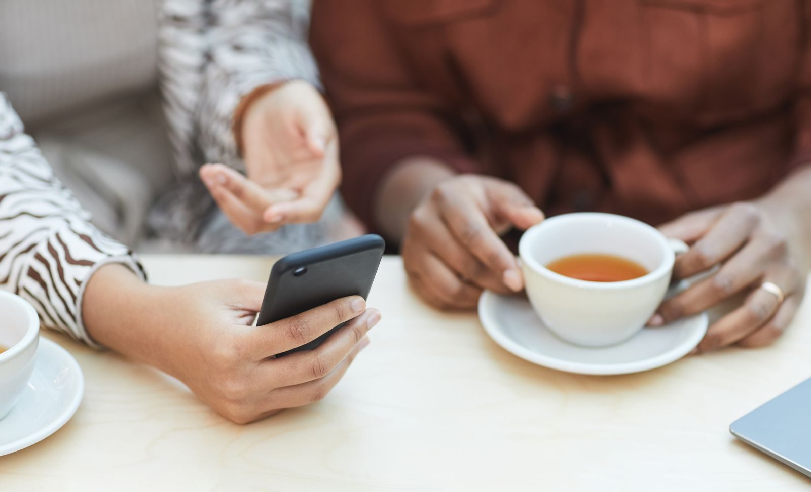 Dois colegas trocando ideias com smartphone e café em ambiente colaborativo