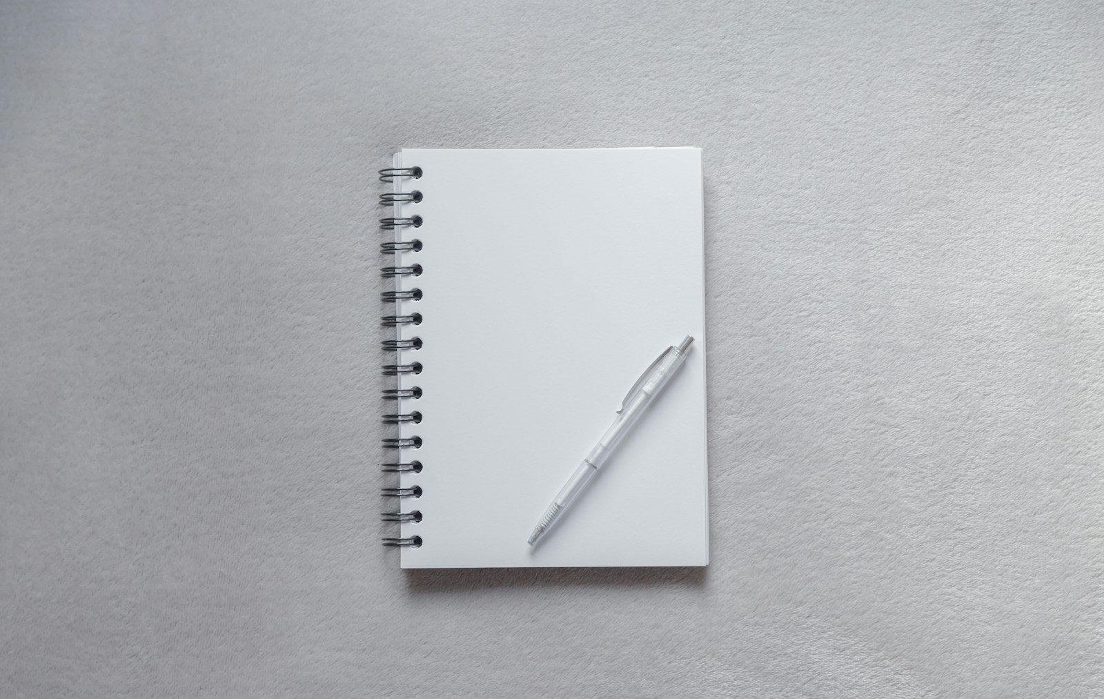 Caderno branco com caneta por cima
