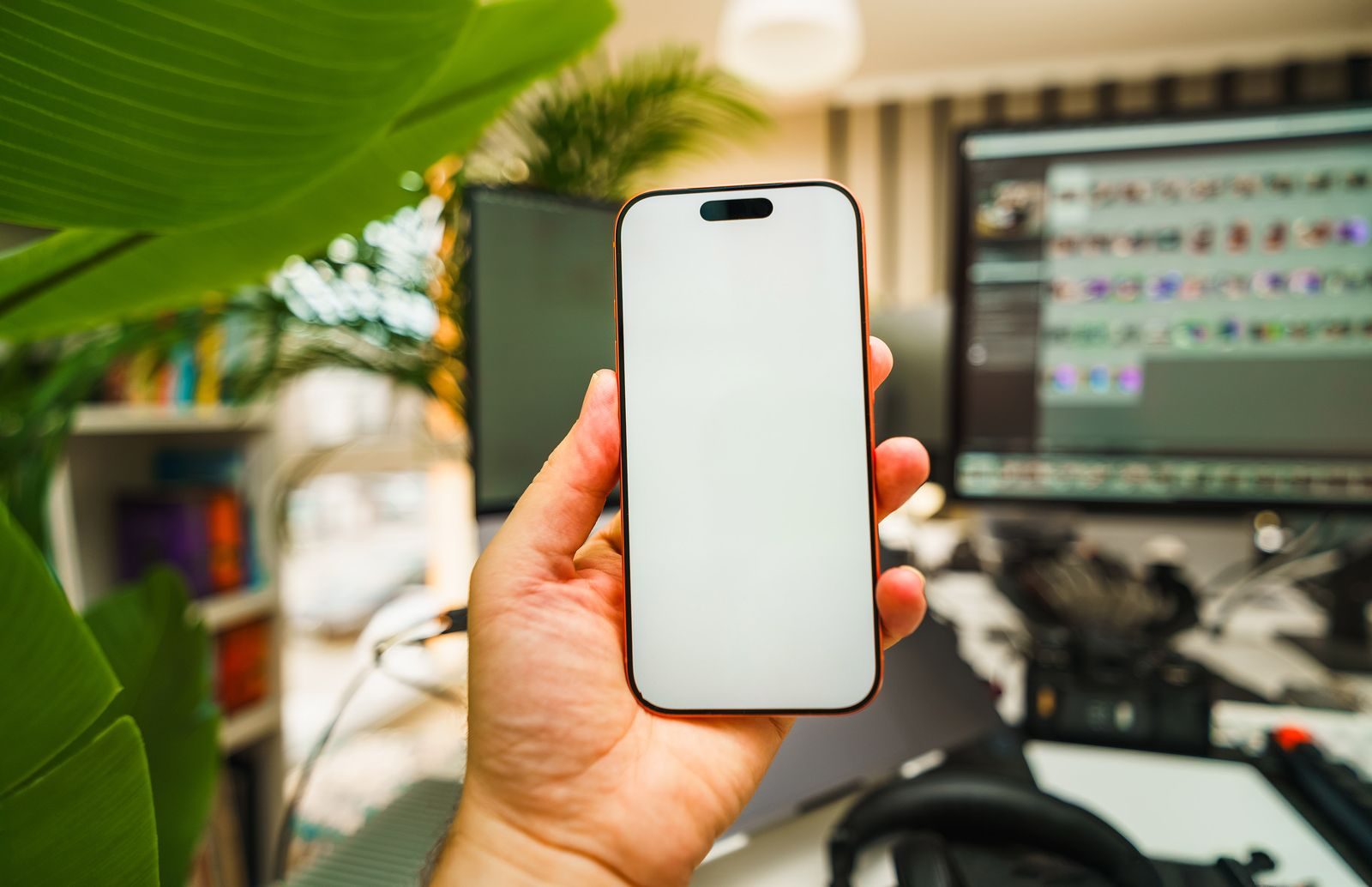 Close de mão segurando um smartphone com tela em branco em um escritório