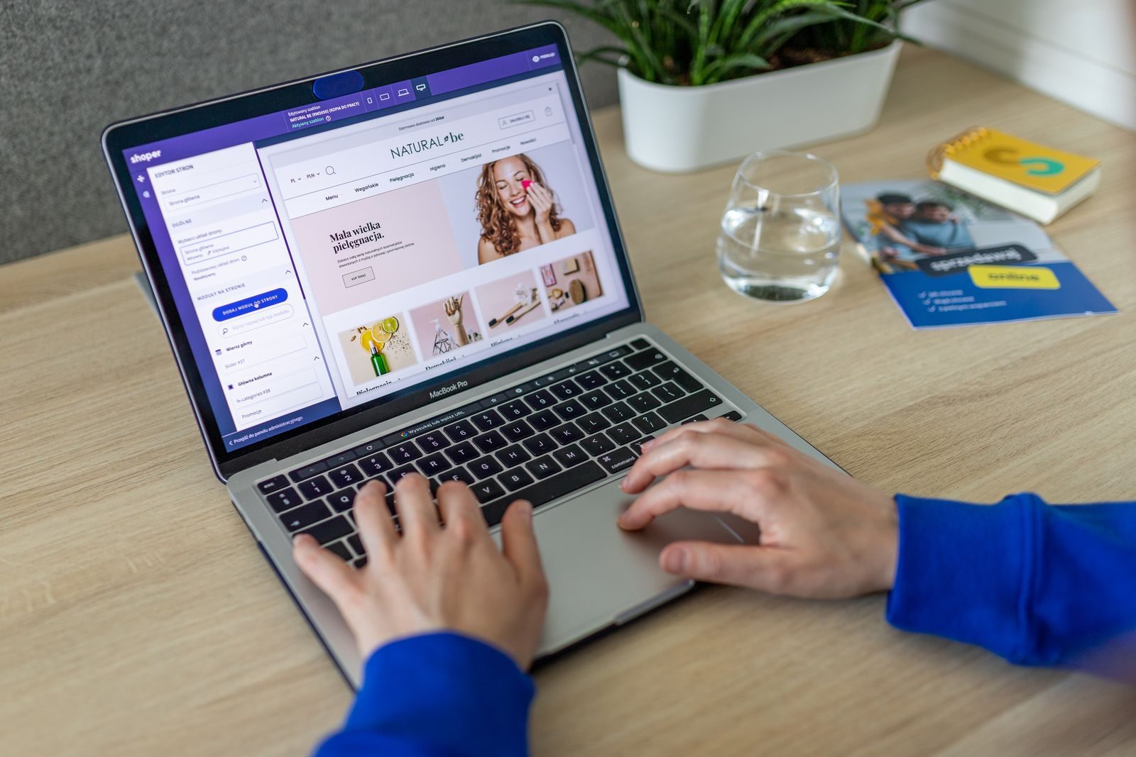 Mãos digitando em um notebook com um site de e-commerce em um escritório moderno