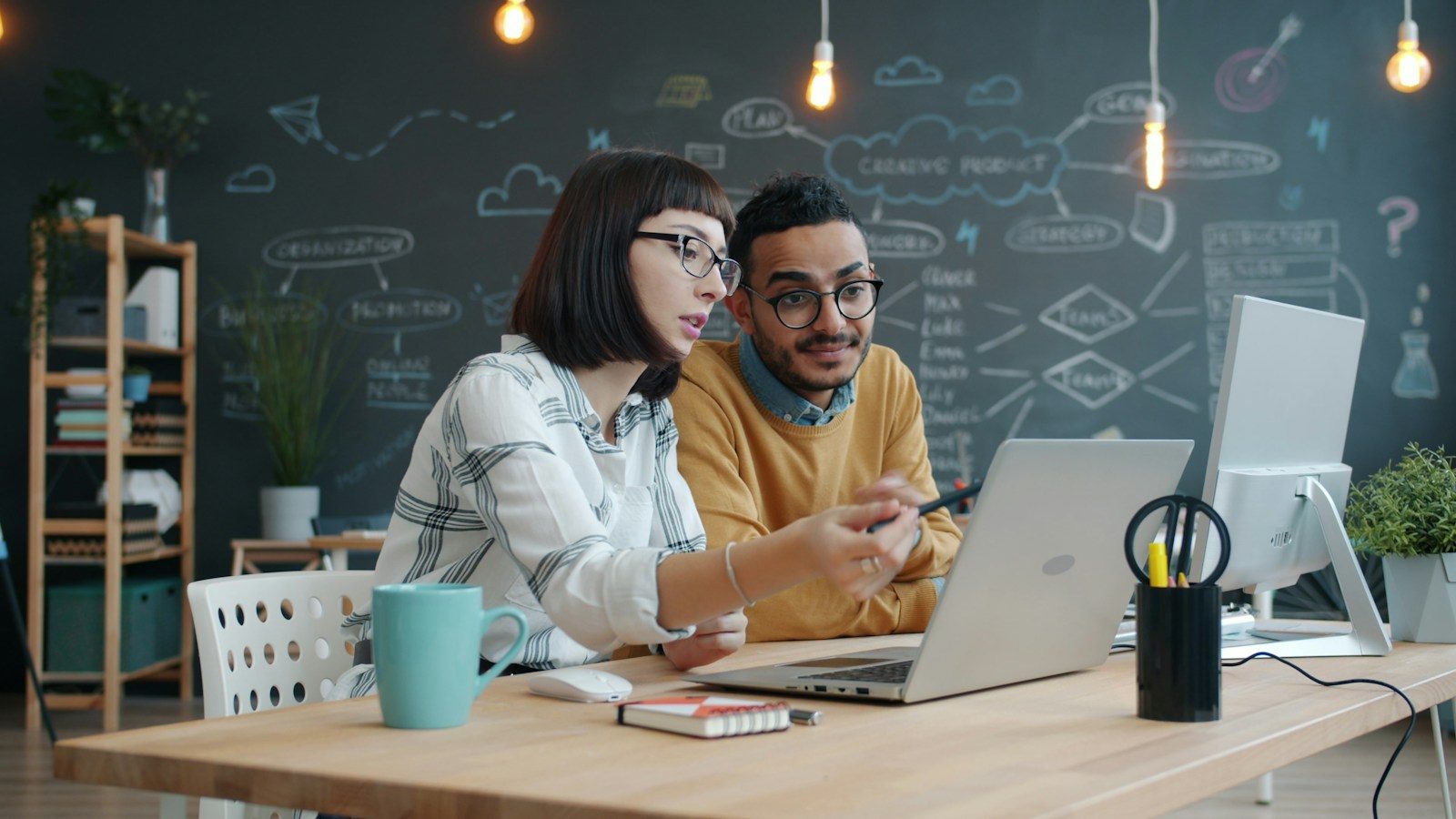 Dois colegas colaborando em um notebook em uma mesa