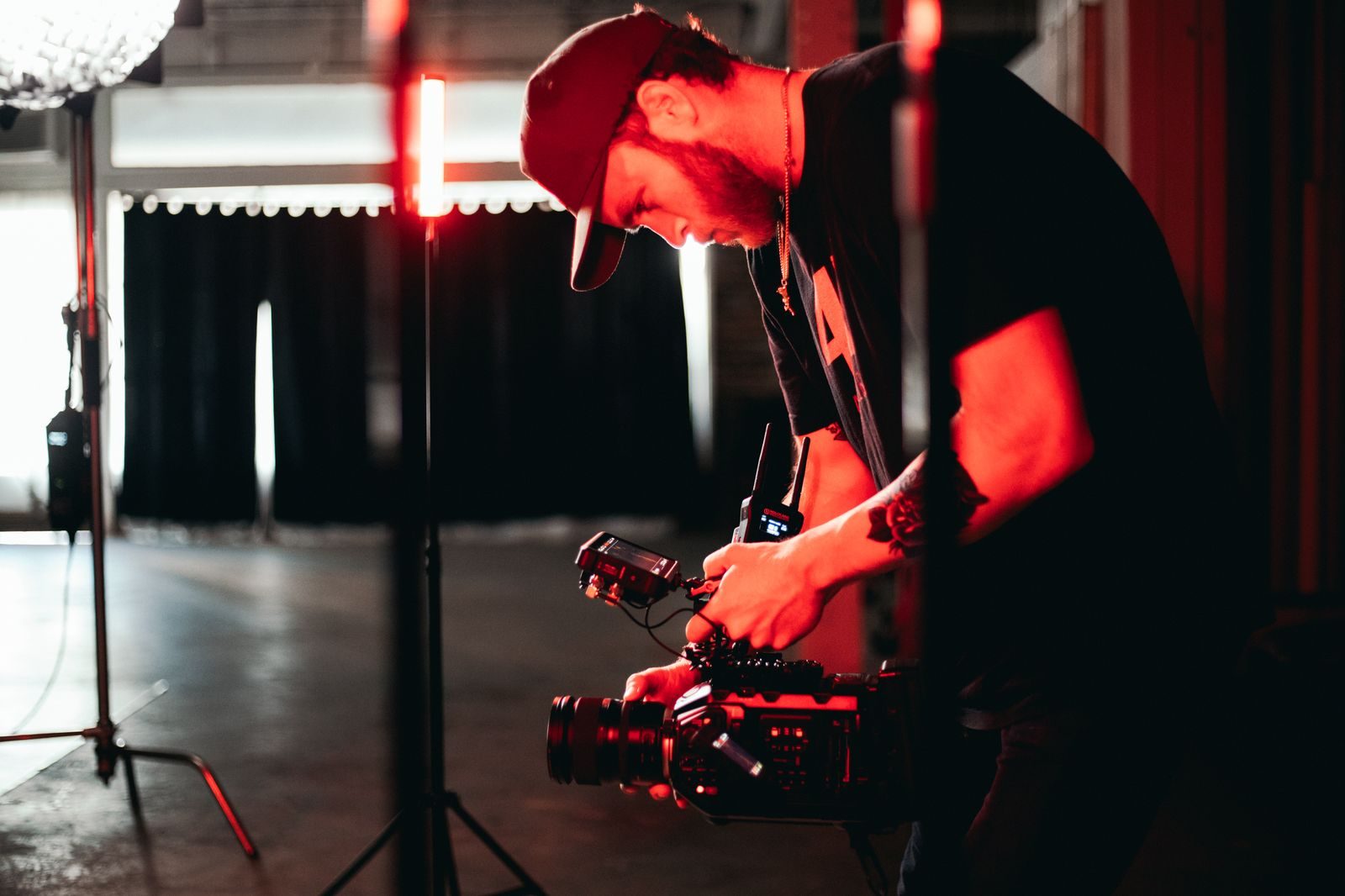 Videomaker ajustando equipamento de câmera em um estúdio com pouca luz