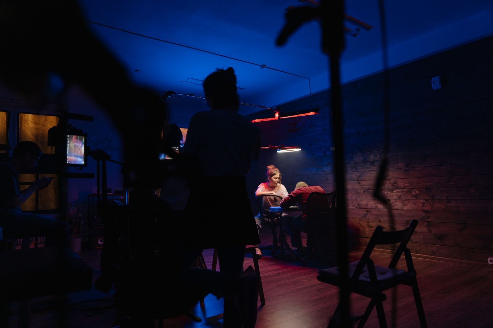 Equipe criativa trabalhando em estúdio com luz neon e equipamentos de câmera