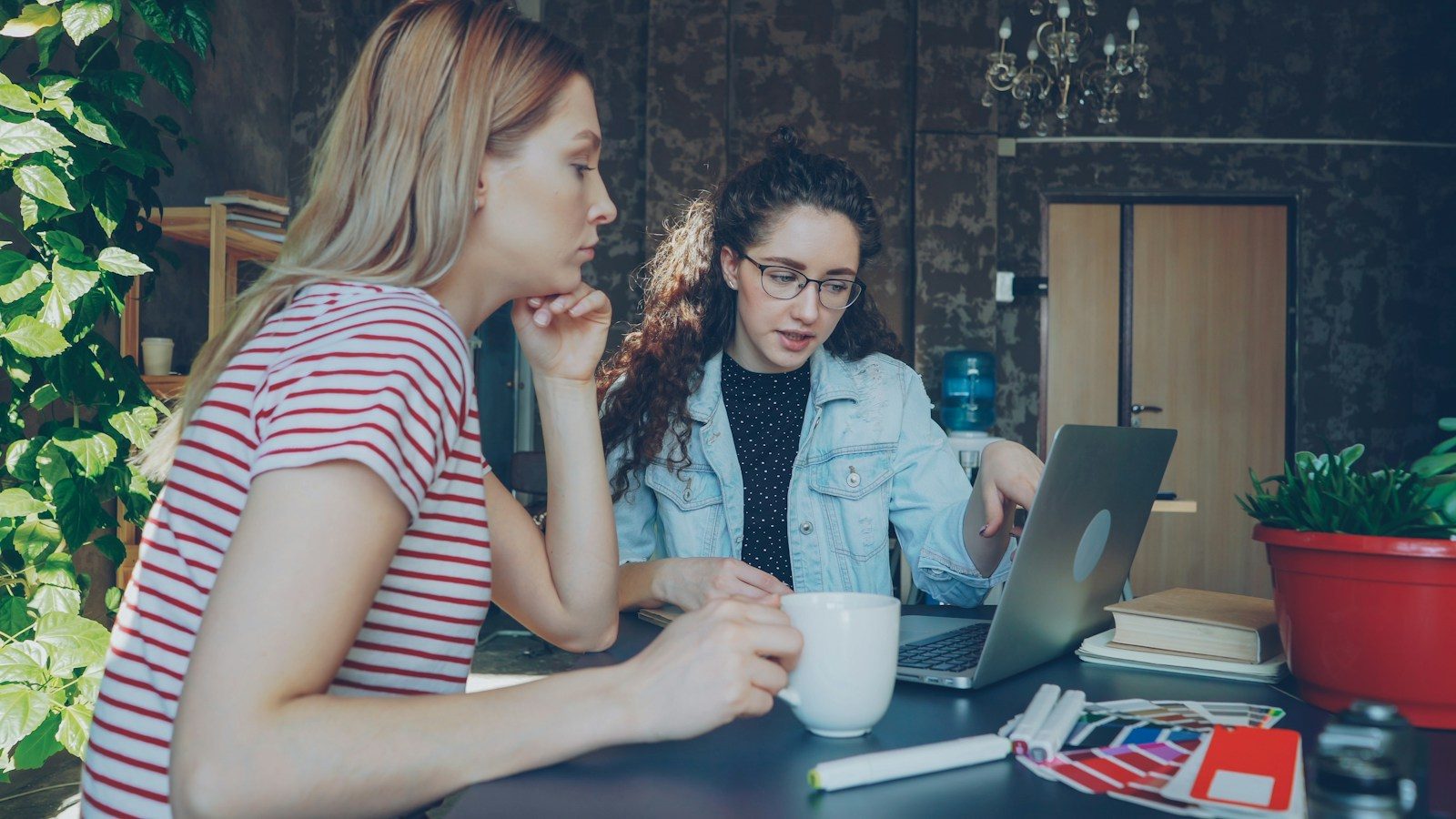 Duas mulheres conversam sobre algo em um notebook