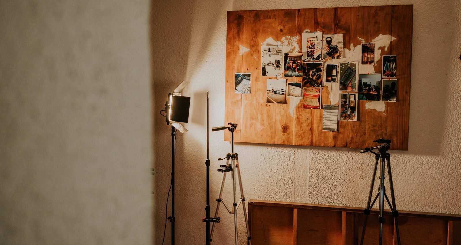 Canto de estúdio fotográfico com equipamentos de iluminação e painel de colagens na parede