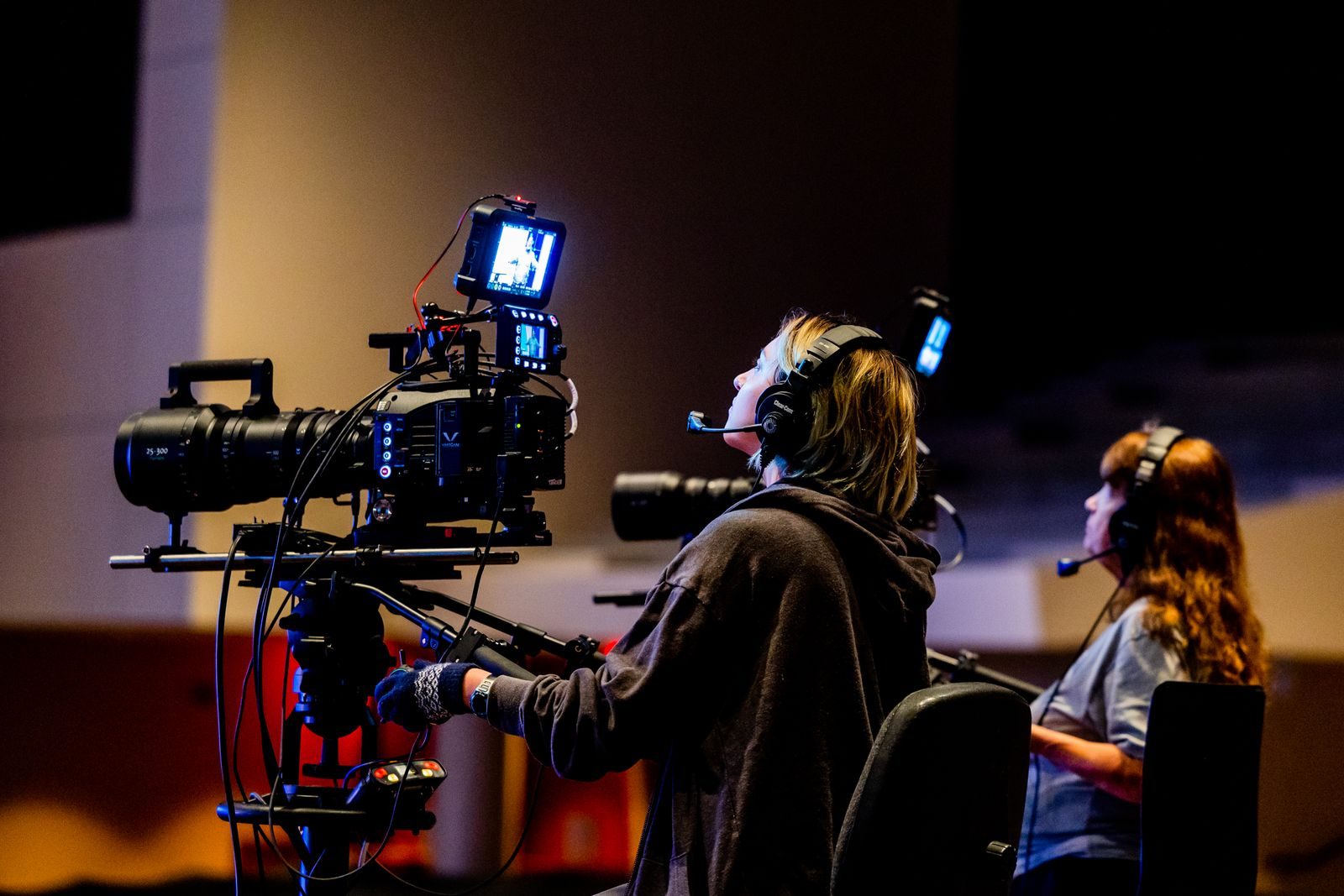Equipe de filmagem concentrada operando câmeras de alto padrão em uma gravação interna