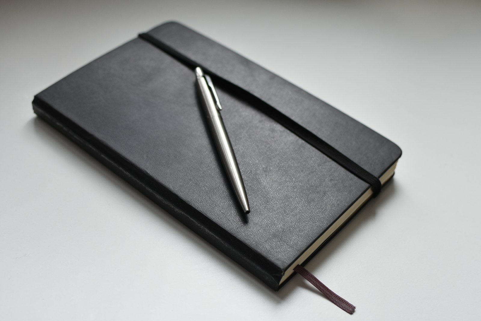 Caneta prateada retrátil sobre livro preto
