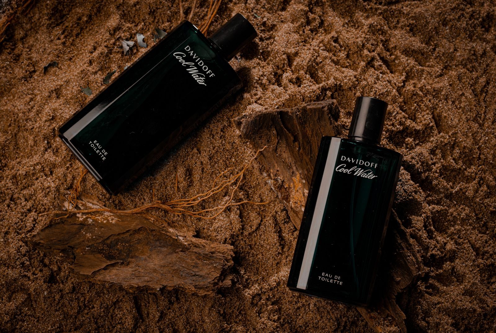 Close de frascos de perfume elegantes sobre fundo de areia
