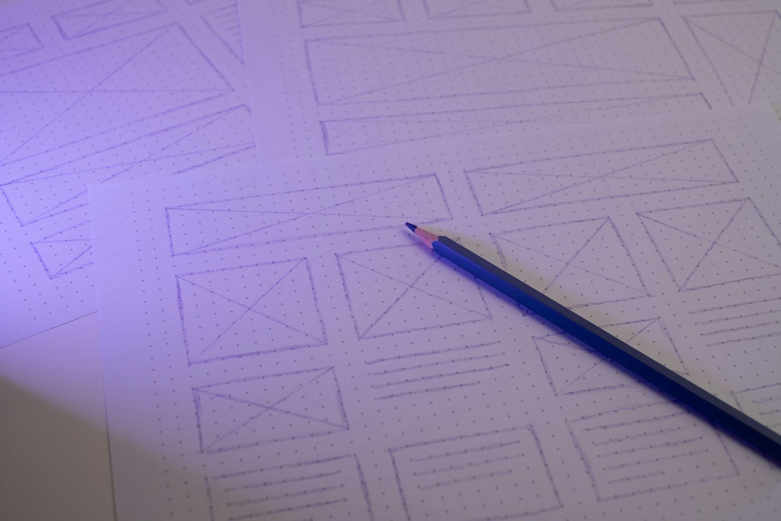 Lápis sobre papel pontilhado com wireframes de site desenhados à mão
