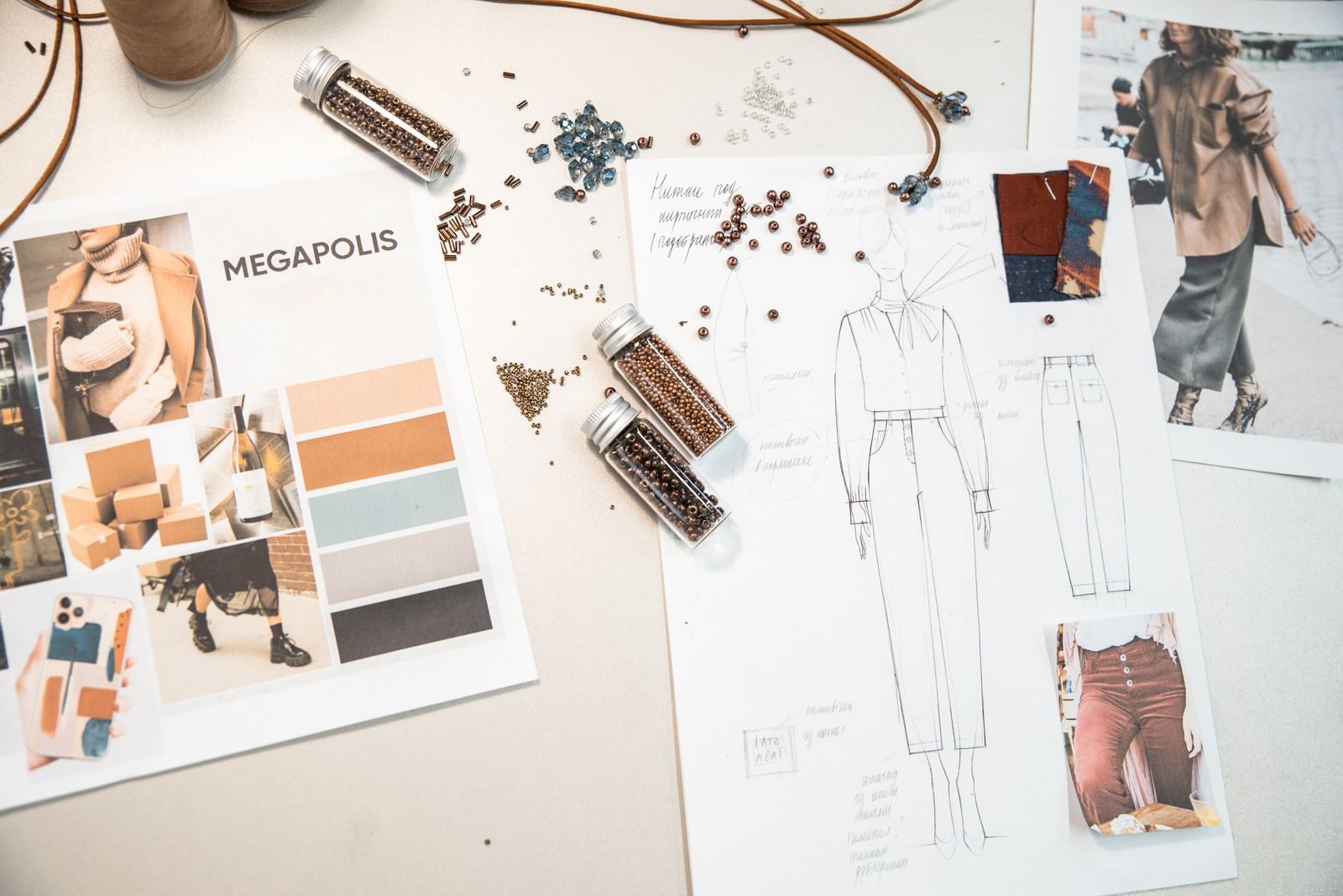 Espaço de trabalho de moda com esboços, painéis de inspiração e miçangas sobre a mesa