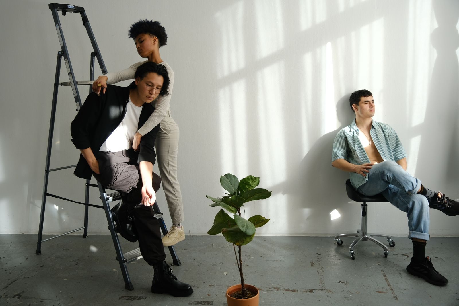 Grupo de modelos posando em estúdio minimalista com luz do sol e uma escada