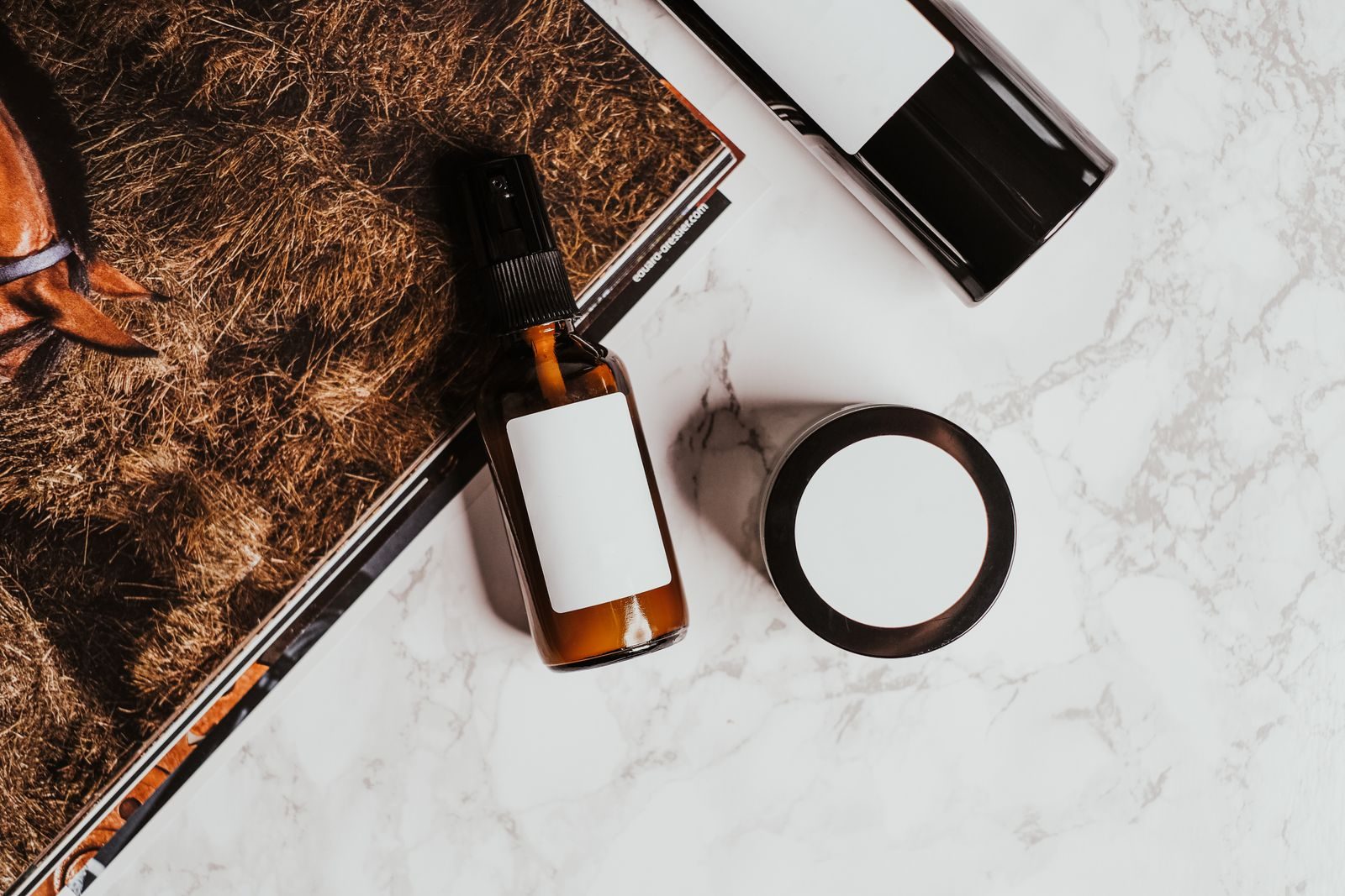 Flat lay de produtos de skincare com revista sobre superfície de mármore