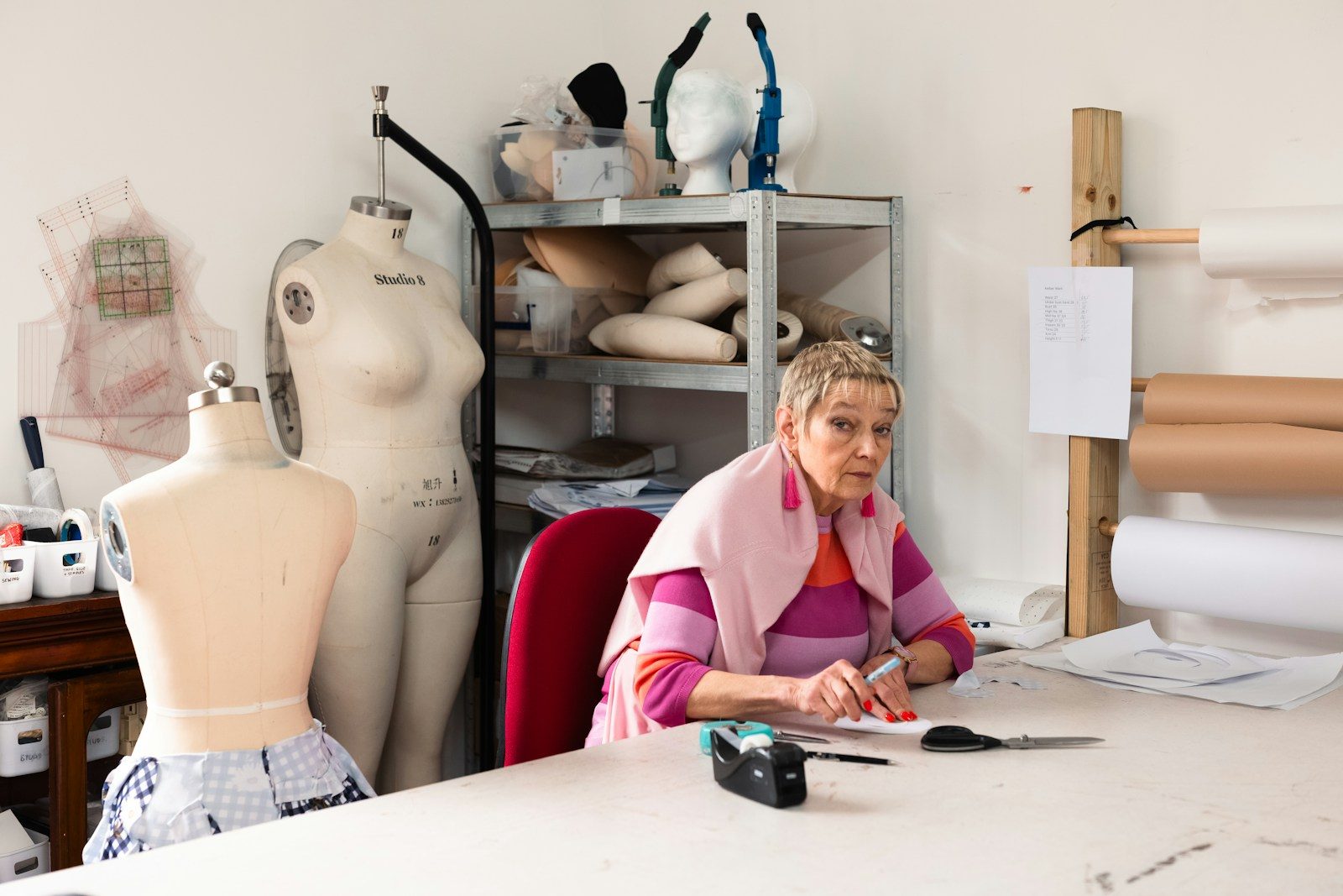 Mulher trabalhando em uma mesa de costura com manequins