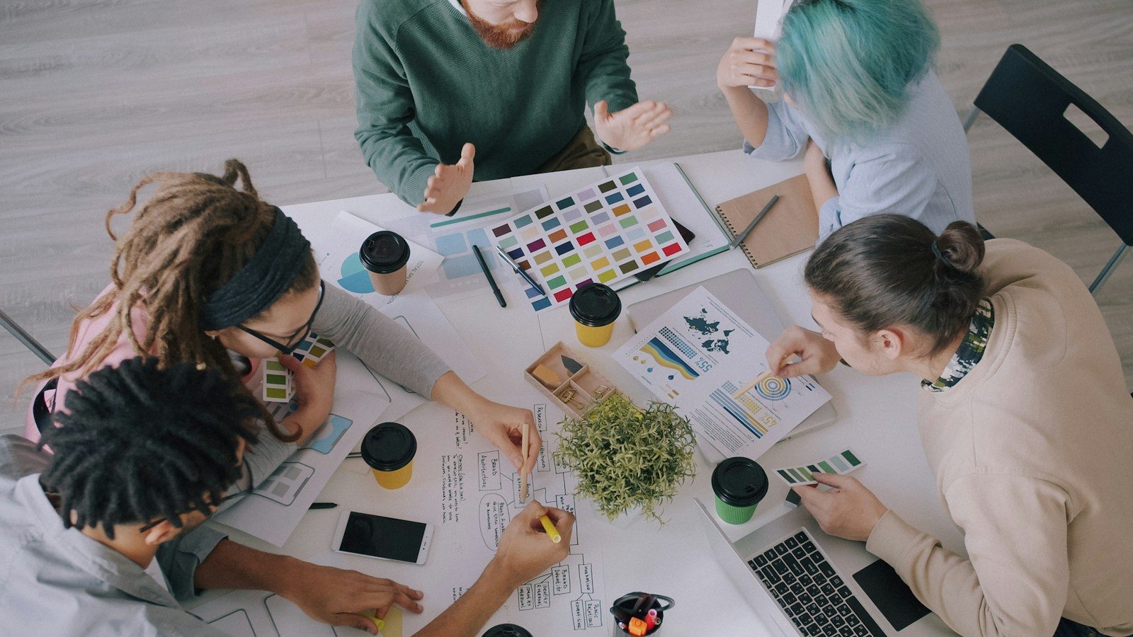 Grupo de pessoas colaborando em projetos de design em uma mesa de espaço de trabalho