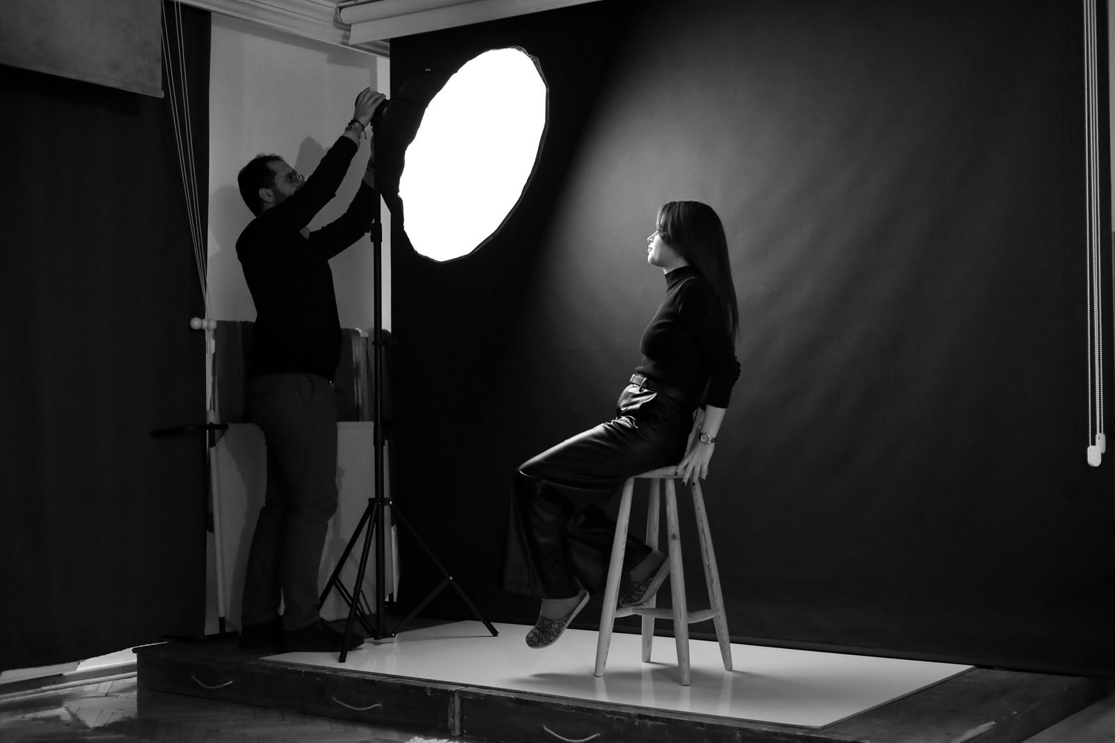 Fotógrafo ajustando a iluminação para modelo sentada em um banco