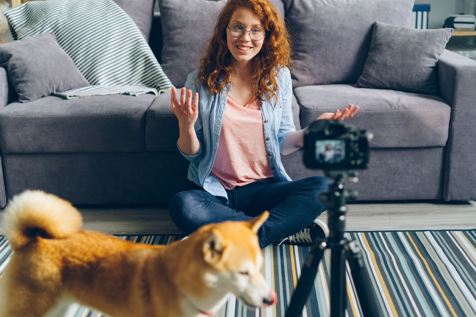 Mulher ruiva gravando vídeo em casa com seu cachorro em uma sala aconchegante