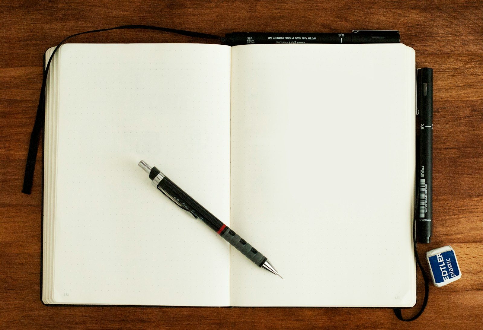 Caneta retrátil preta e prateada sobre caderno em branco