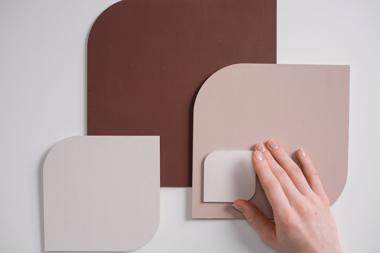 Arranjo minimalista de amostras de cor com uma mão tocando-as suavemente